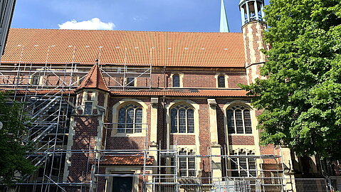 Die seitliche Ansicht der Petrikirche zeigt trotz Gerüst die Wandgestaltung mit rotem Backstein und hellem Sandstein. 