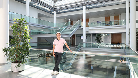 Männlich gelesene Person im Foyer eines Gebäudes.