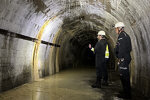 Blick in einen dunklen, gewölbten Stollentunnel unter Dortmund – am Ende leuchtet ein helles Licht.
