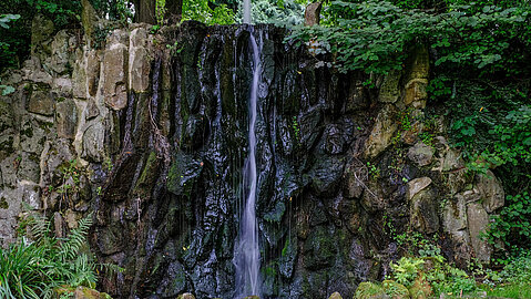 Ein kleiner Wasserfall fließt die Steinwand hinunter.