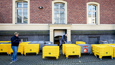Dokumentenlieferung für das Land- und Amtsgericht Duisburg. Zwei Personen stehen mit rund 30 Rollwagen vor dem Gericht.