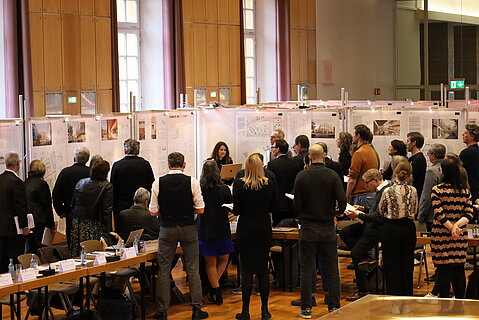 Gäste und Beobachtende beim Wertungsrundgang der Preisgerichtssitzung Viktoriakarree in der Aula der Universität Bonn