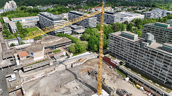 Ein riesiger gelber Kran steht in der Baugrube für das neue NA-Gebäude an der RUB.