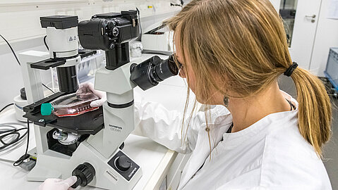 Frau schaut durch ein Mikroskop
