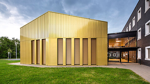 In der Bildmitte ist der neu gebaute Musiksaal, dessen goldene Außenfasse im Licht glänzt.
