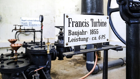 An der Pumpe ist ein Schild mit dem Baujahr 1855 und der Leistung der Turbine befestigt.