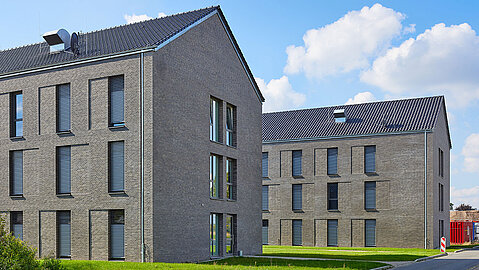 Zwei Moderne Unterkunftsgebäude, die aussehen wie Mehrfamilienhäuser. Sie haben eine dunkle Klinkerfassade.