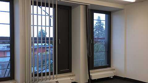Blick in ein fertig saniertes Zwei-Personen-Büro mit neuen Fenstern, neuem Boden und neuer LED-Beleuchtung.