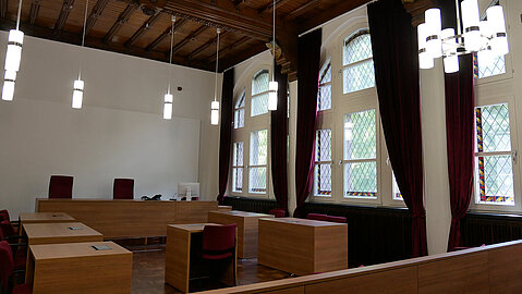Ein Sitzungssaal im Amtsgericht mit hölzerner Decke und großen Fenstern.