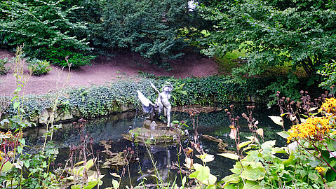 Ein Junge mit Schwan ziert den Schwanenteich im Garten. 