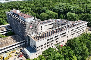 Aufnahme des modernisiertes Gebäudes mit der Drohne: Sicht auf Dach mitsamt PV-Anlage sowie neue Fassade.