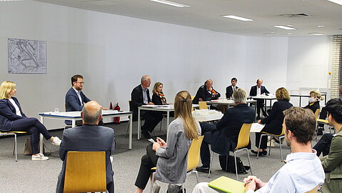 Eine Gruppe von Menschen sitzt einer anderen für das Kolloquium gegenüber.