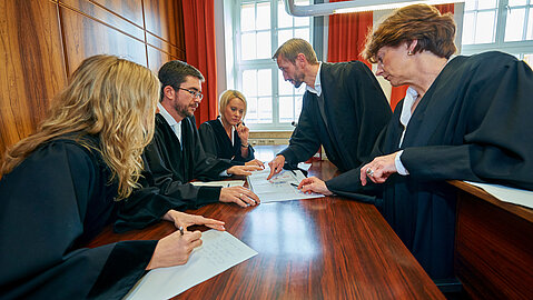 Staatsanwalt, Richter und Verteidiger treffen sich zu Besprechung an der Richterbank.