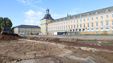 Das ehemalige Kurfürstliche Schloss in Bonn mit Bautätigkeit im Vordergrund und einem Baustellenfahrzeug.. 