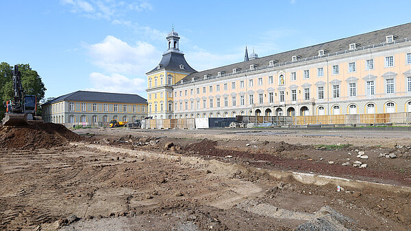 Das ehemalige Kurfürstliche Schloss in Bonn mit Bautätigkeit im Vordergrund und einem Baustellenfahrzeug.. 
