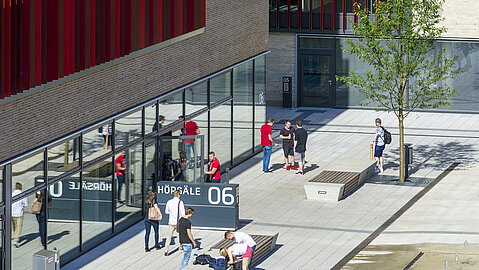 Vor dem Gebäude des Hörsaal 06 stehen Studenten.