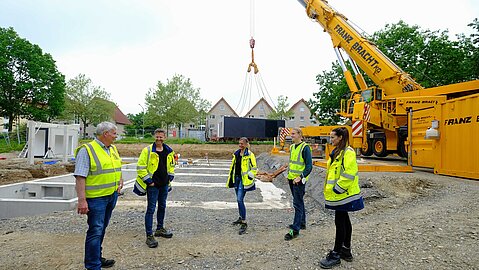 Das Projektteam steht auf der Baustelle und bespricht sich.