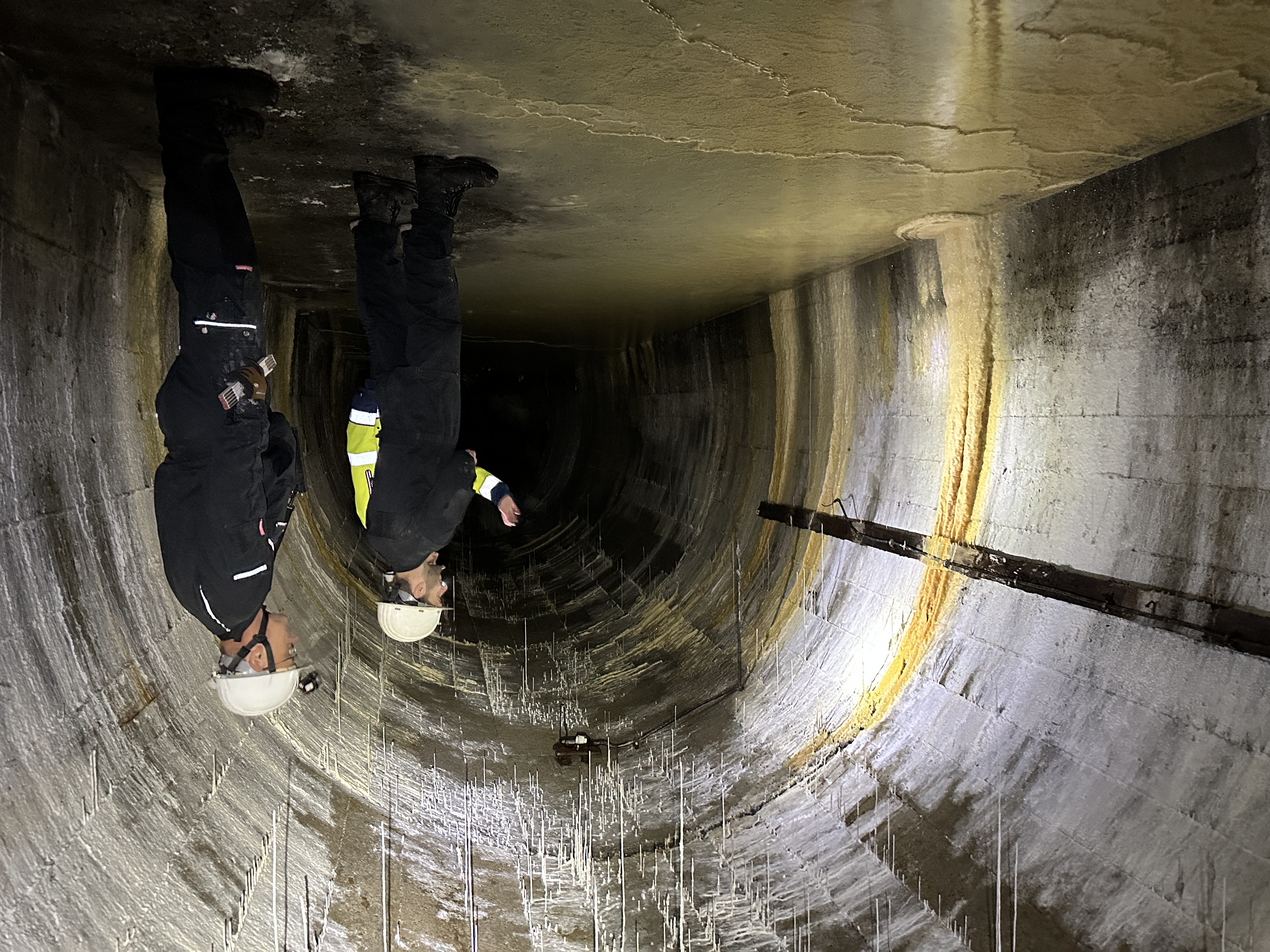 Blick in einen dunklen, gewölbten Stollentunnel unter Dortmund – am Ende leuchtet ein helles Licht.